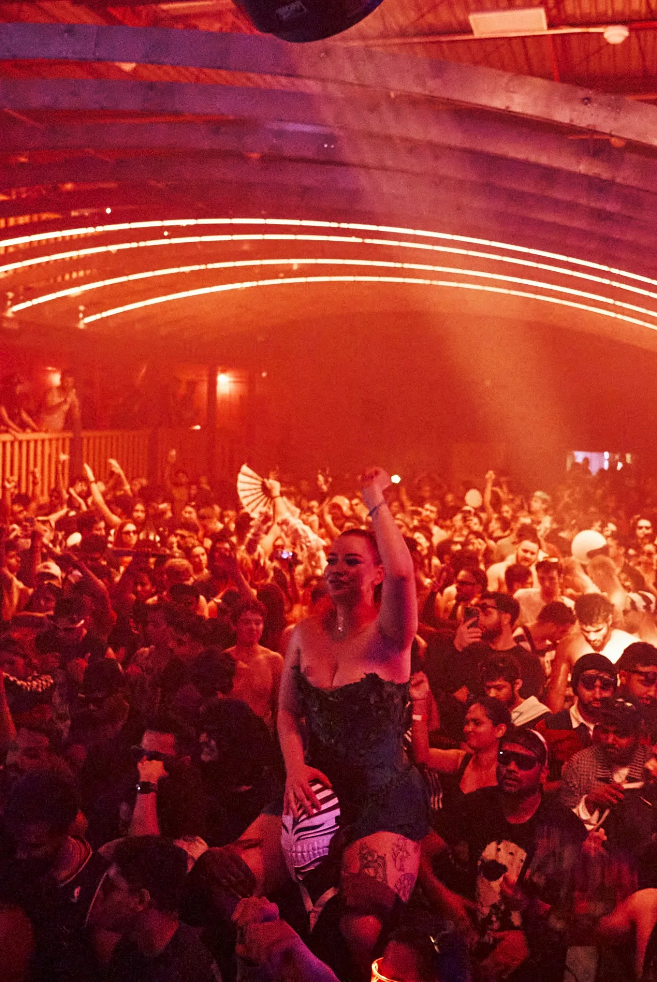 The INFERNØ 2025 crowd under red lighting, with guests dancing and raising their hands